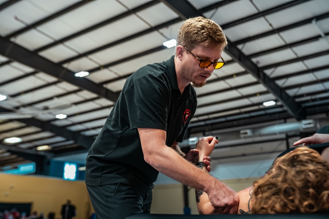 Trey performing arm and shoulder mobility work on a roller derby athlete